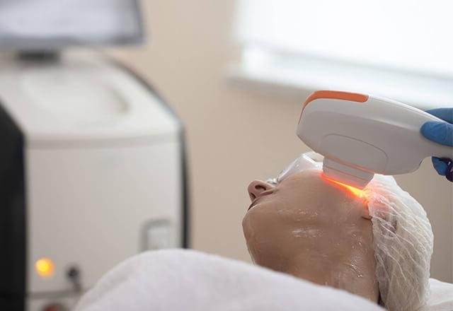 A woman receives laser therapy for facial skin rejuvenation.