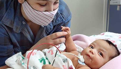 一个躺在医院病床上的婴儿被父母看护着